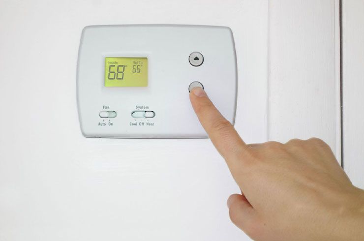a person setting a thermostat