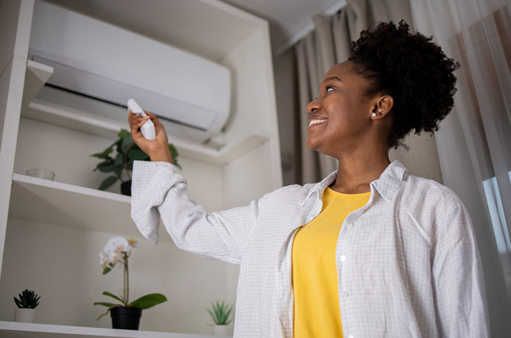 a woman turning on an air conditioner