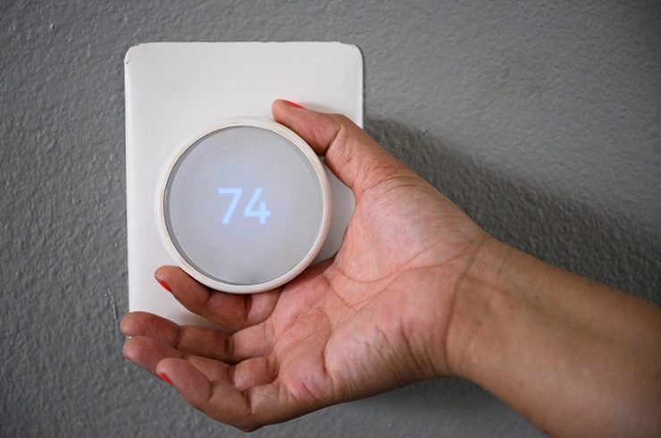 a hand adjusting the temperature on a smart thermostat
